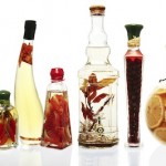 Variety of oil infusions and preserved fruits and vegetables, in fancy glass bottles. Isolated on white, reflected. XXL file.